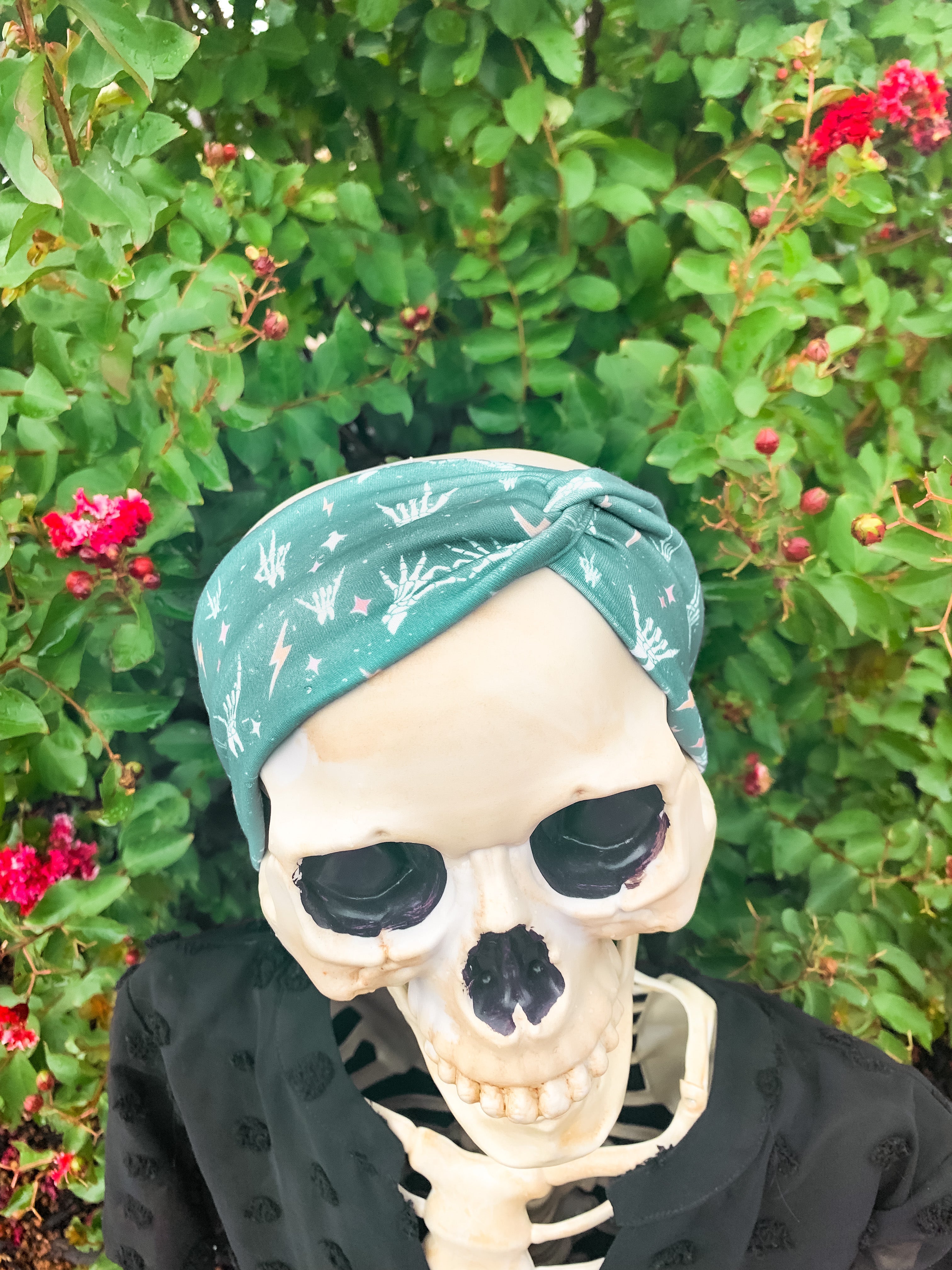 Adult women's emerald green headband with skeleton hands signing love, peace, rock-on and hang-loose shaka sign with yellow lightneing bolts and orange and pink diamonds