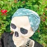 Adult women's emerald green headband with skeleton hands signing love, peace, rock-on and hang-loose shaka sign with yellow lightneing bolts and orange and pink diamonds