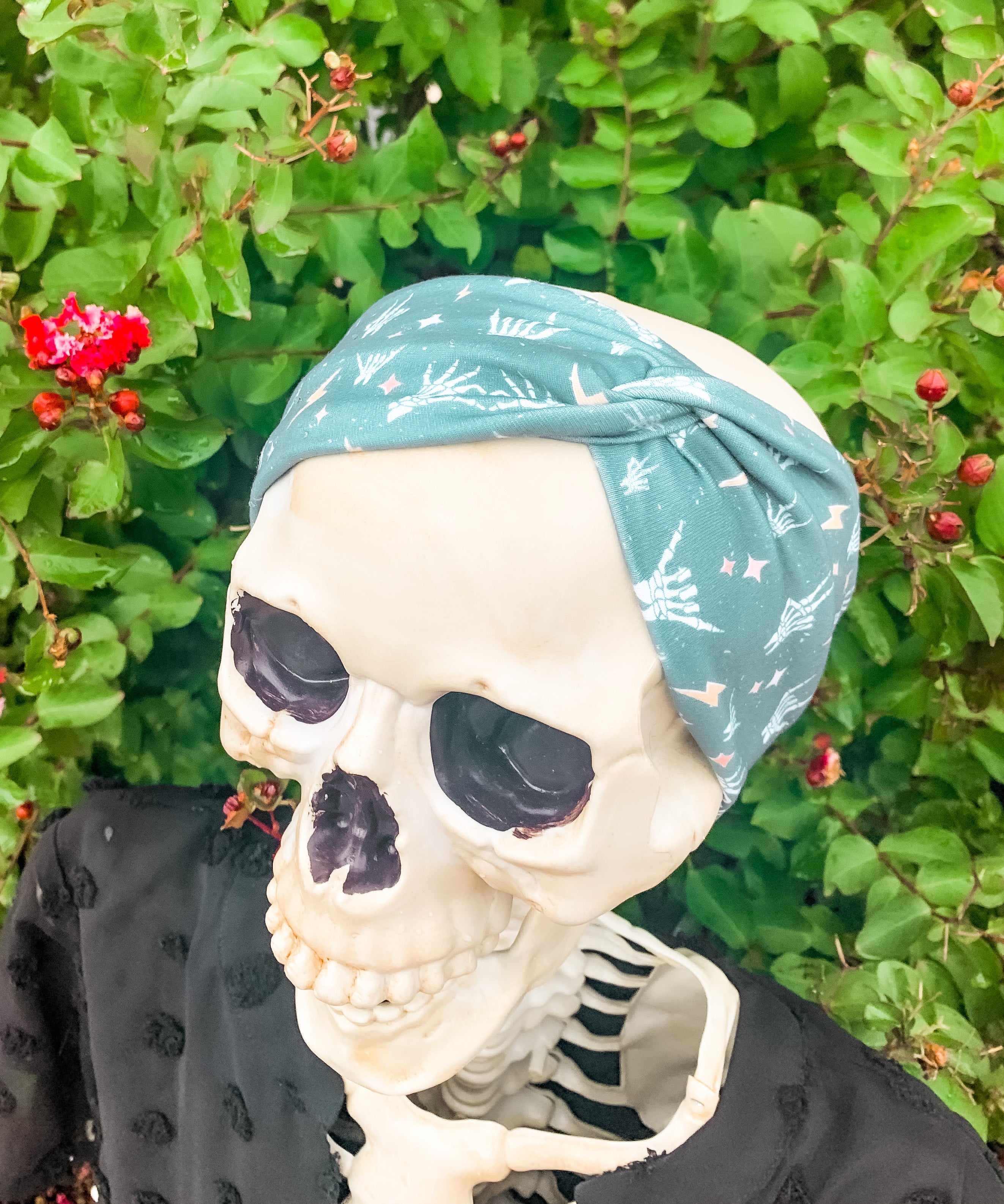 Adult women's emerald green headband with skeleton hands signing love, peace, rock-on and hang-loose shaka sign with yellow lightneing bolts and orange and pink diamonds