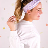 Adult women’s purple headband with medium white, dark and light purple floral allover pattern.