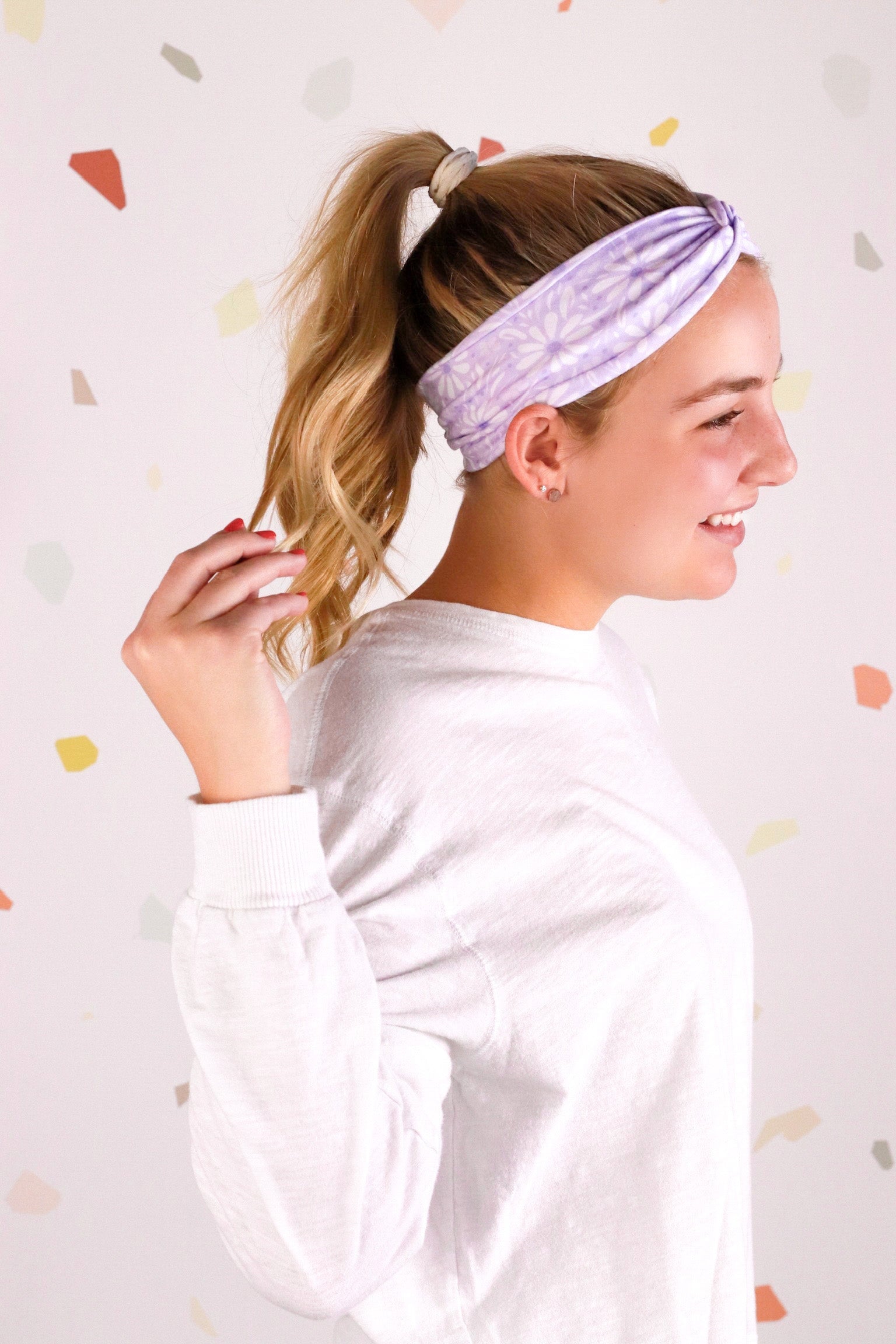 Adult women’s purple headband with medium white, dark and light purple floral allover pattern.