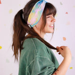 Adult women’s headband with allover layered watercolor paint brushstroke print in varying oranges, pinks, yellows, blues, greens and whites.
