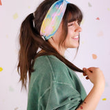 Adult women’s headband with allover layered watercolor paint brushstroke print in varying oranges, pinks, yellows, blues, greens and whites.