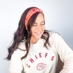 Adult women's red headband with yellow and white 1970's bubble script with the phrase "Chiefs" and an arrowhead