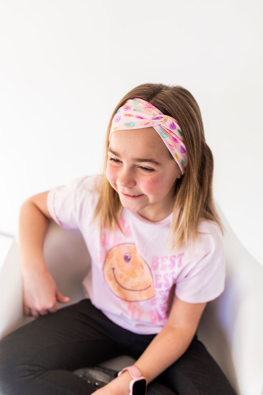 Adult women's peach headband with purple, blue, orange, yellow, green and pink candy hearts with various Valentine's sayings