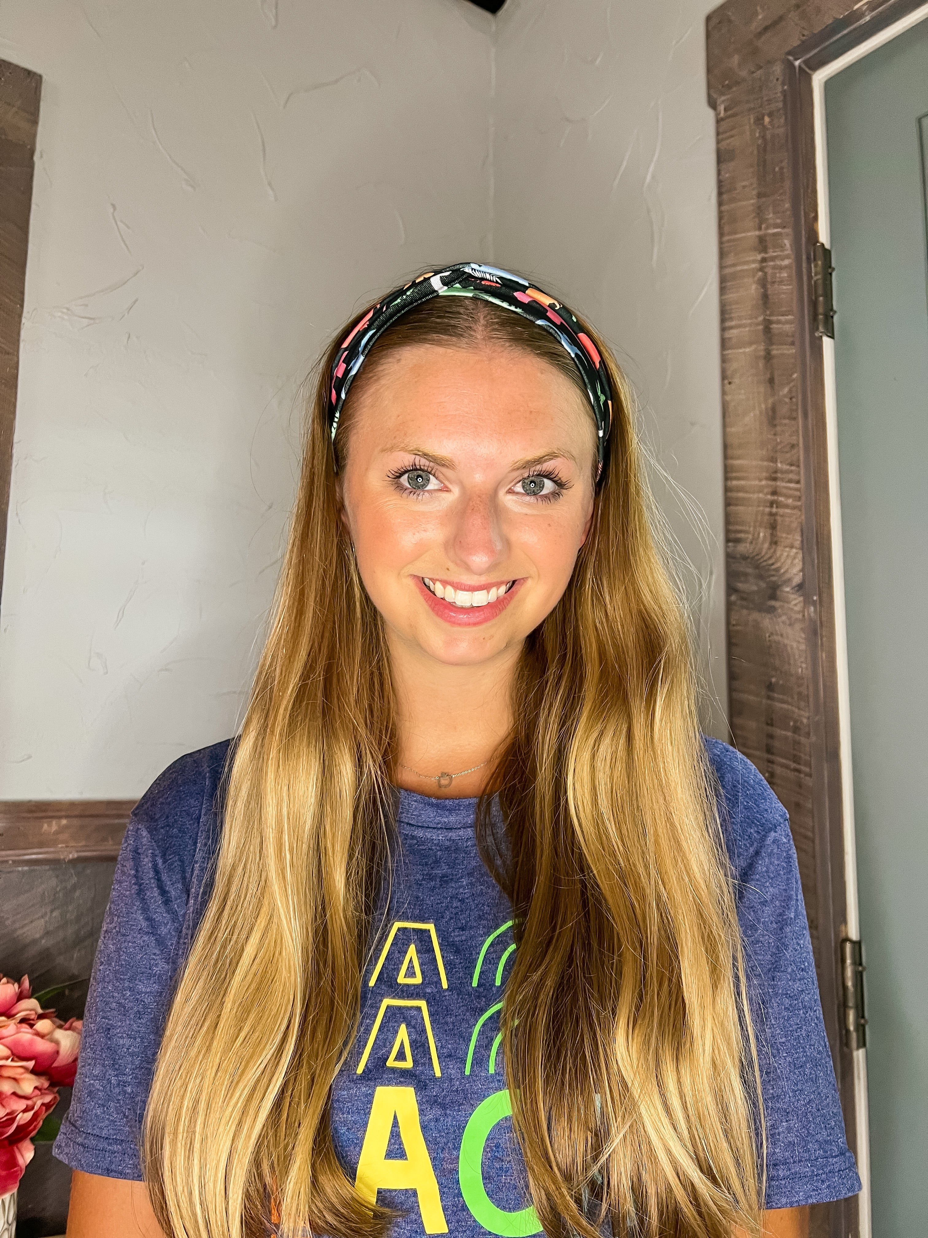 Adult women's black headband with orange, red, blue, grey and pink dinosaur silhouettes with similar colored plants