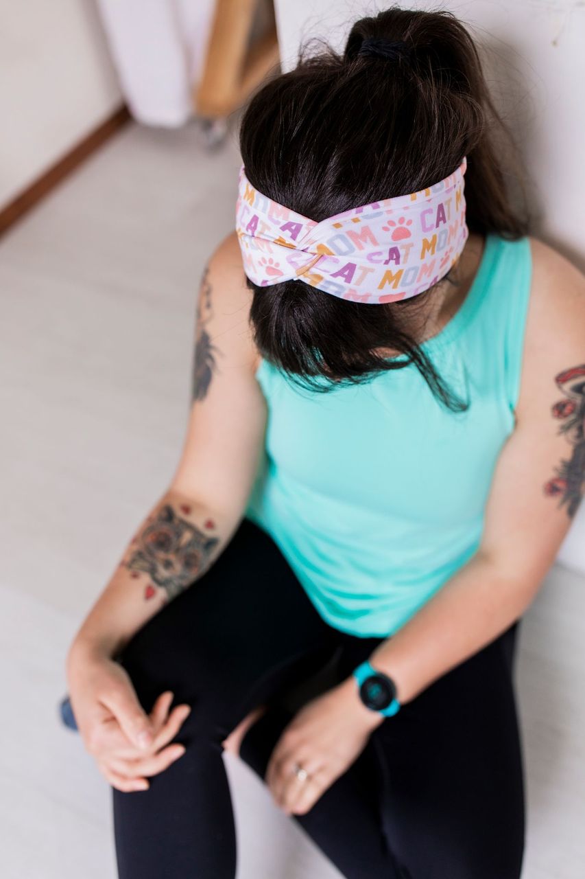 Adult women's white headband with orange, slate, tan, blush and plum pawprints, hearts and words they say "cat mom"