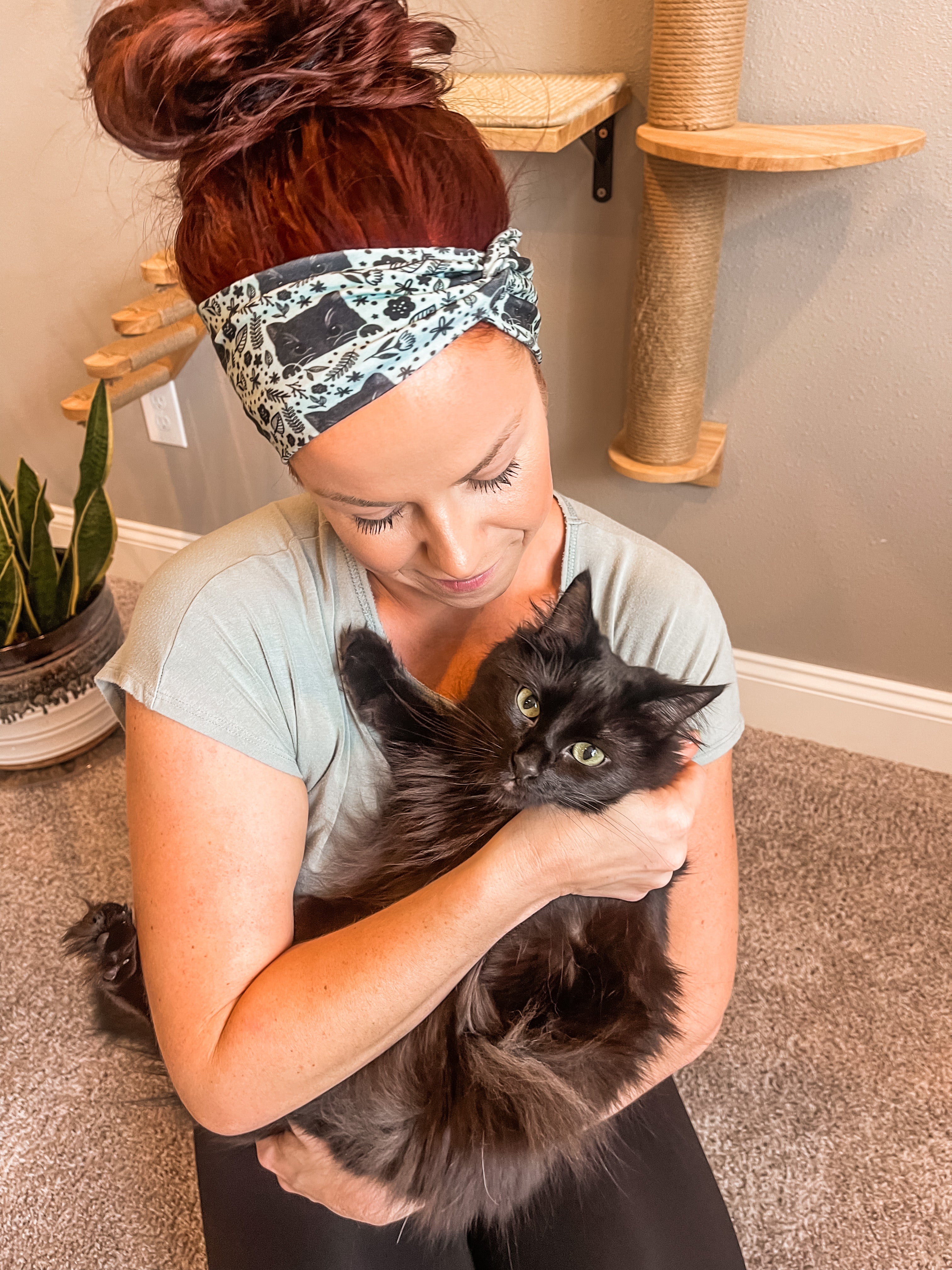 Adult women's sage headband with black cat art peaking over with small black flower and dot outlines