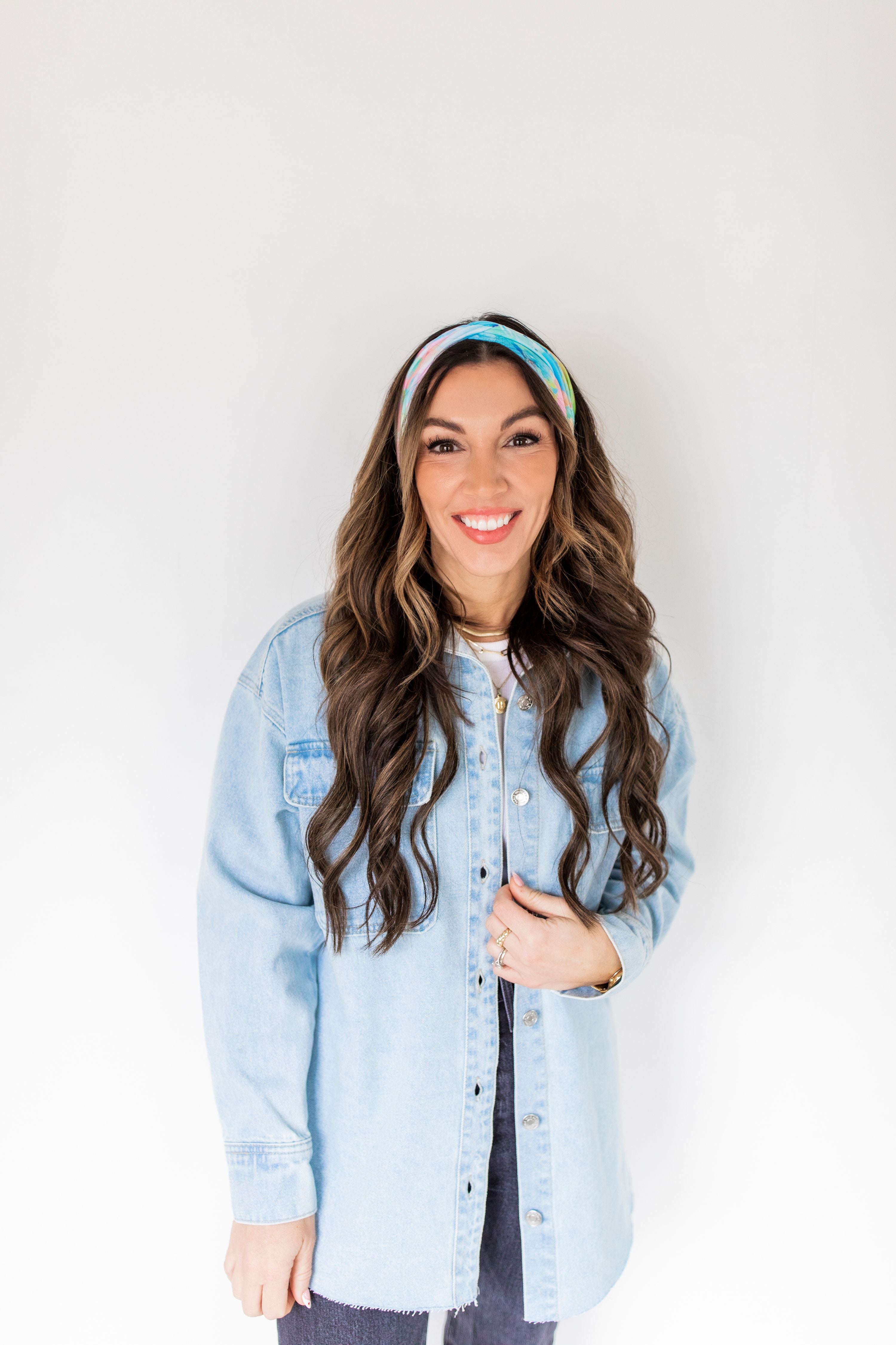 Adult women’s headband with allover layered watercolor paint brushstroke print in varying oranges, pinks, yellows, blues, greens and whites.