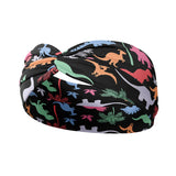Adult women's black headband with orange, red, blue, grey and pink dinosaur silhouettes with similar colored plants