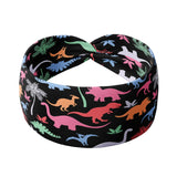 Adult women's black headband with orange, red, blue, grey and pink dinosaur silhouettes with similar colored plants