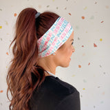 Adult women's white headband with pink and blue allover text saying "nurse"