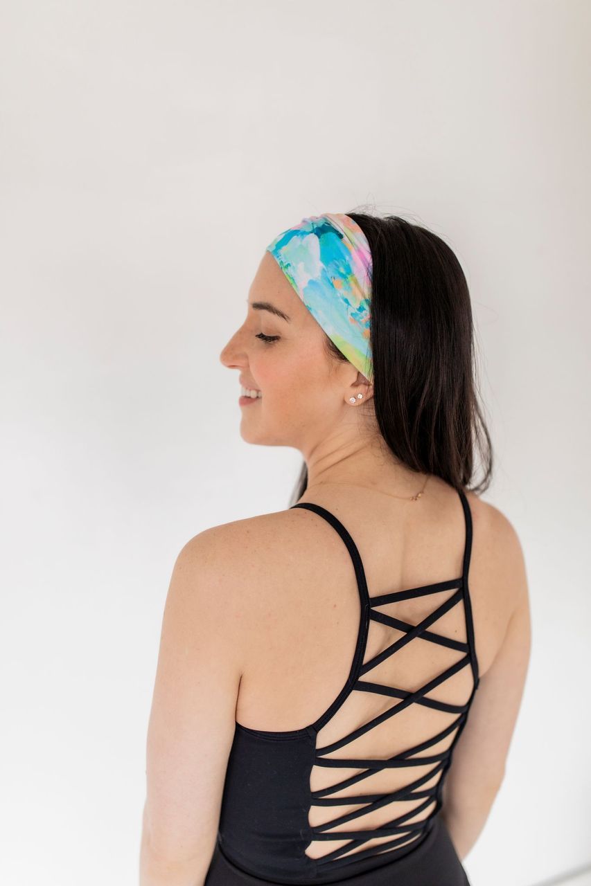 Adult women’s headband with allover layered watercolor paint brushstroke print in varying oranges, pinks, yellows, blues, greens and whites.