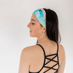 Adult women’s headband with allover layered watercolor paint brushstroke print in varying oranges, pinks, yellows, blues, greens and whites.