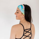 Adult women’s headband with allover layered watercolor paint brushstroke print in varying oranges, pinks, yellows, blues, greens and whites.