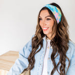 Adult women’s headband with allover layered watercolor paint brushstroke print in varying oranges, pinks, yellows, blues, greens and whites.