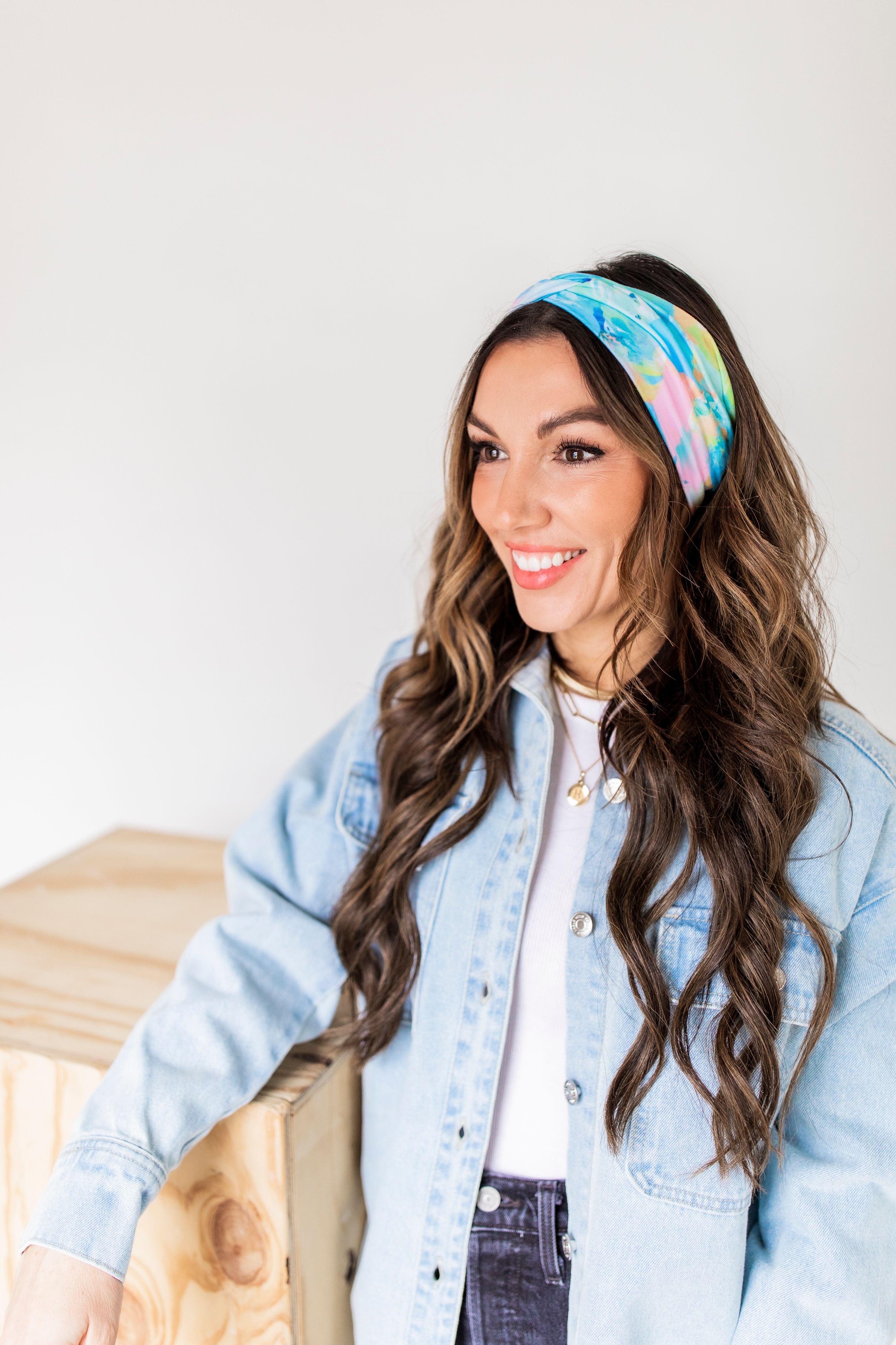 Adult women’s headband with allover layered watercolor paint brushstroke print in varying oranges, pinks, yellows, blues, greens and whites.